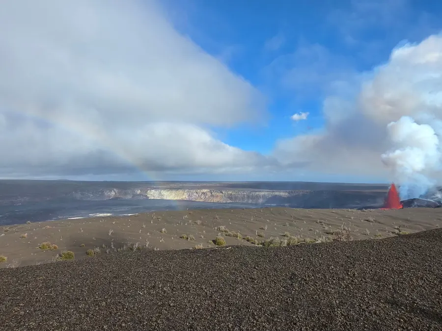 Kīlauea's vast caldera with a glowing lava vent in the distance