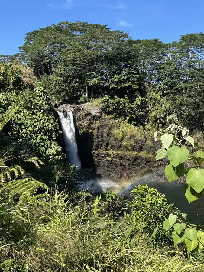 A waterfall and faint rainbow in lush Hilo greenery